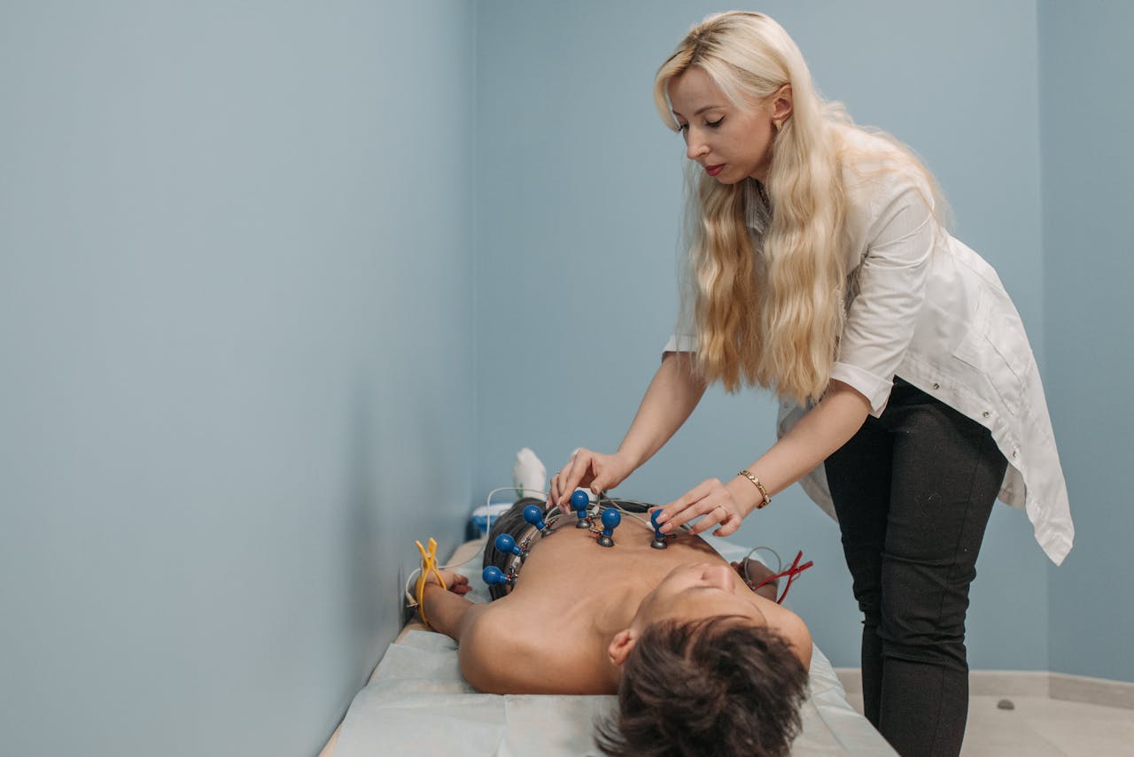 A medical technician attaches sensors for an ECG test in a clinic setting.