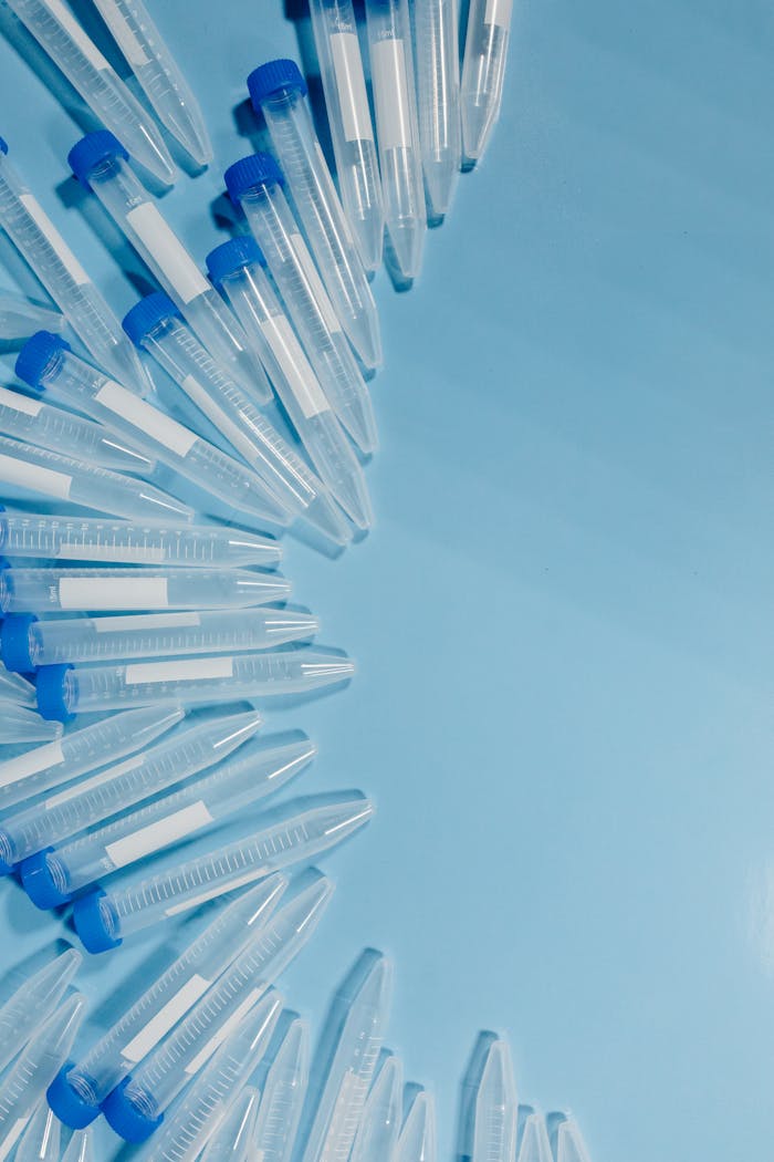 Clear laboratory test tubes with blue caps arranged on a blue background.